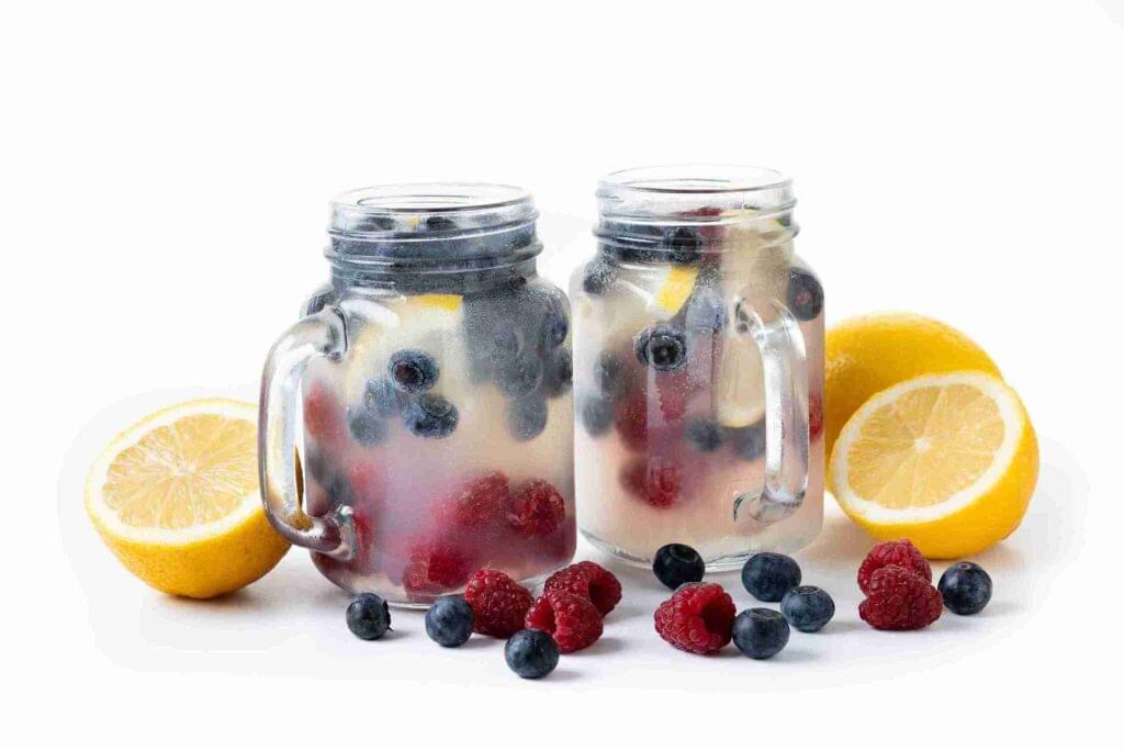 two jars of bluerry lemonade sprite with lemons around it